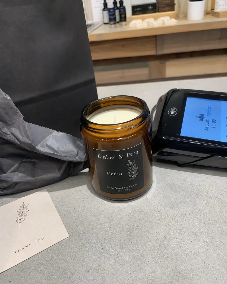 An Ember & Fern cedar candle on a boutique checkout counter